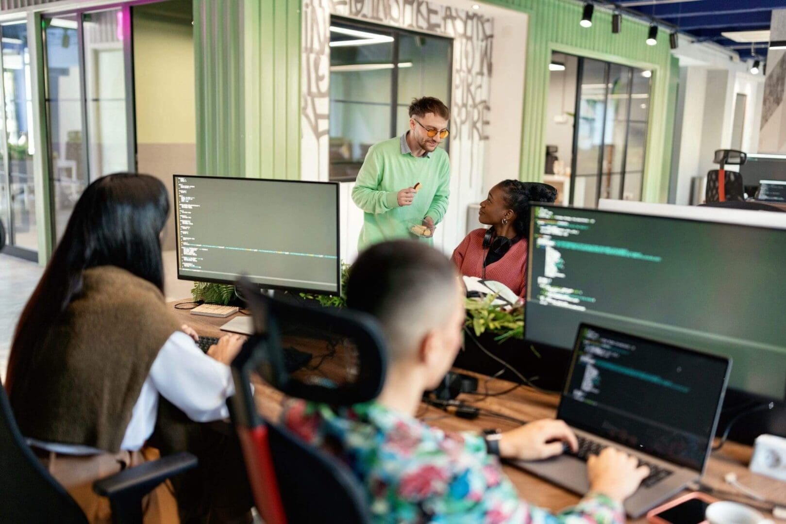 People collaborating on coding projects in an office.