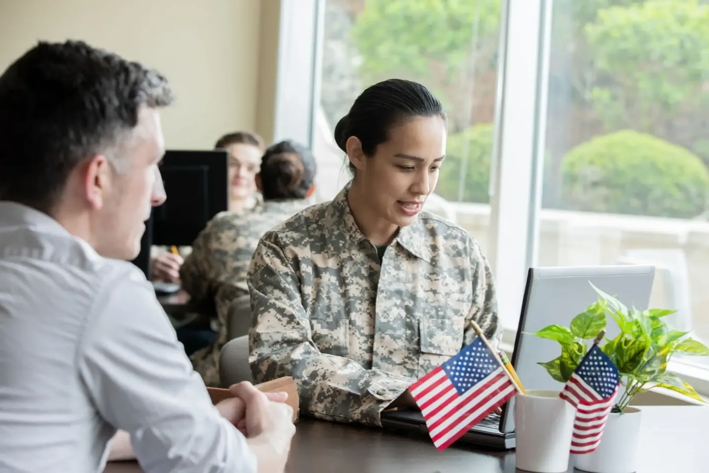A soldier showing a small American flag to a civilian indoors.